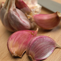 GARLIC BULB AND CLOVES ON WOODEN CHOPPING BOARD WITH KITCHEN KNIFE