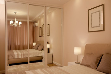 epmty minimalistic interior background, bedroom of modern apartment with big mirrors, double bed, lights on