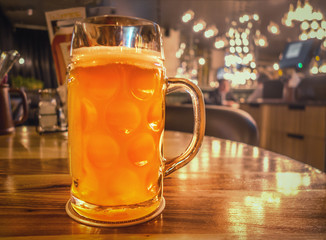 a mug of unfiltered beer, a source of B vitamins and healthy enzymes, on a polished table in a restaurant still life background