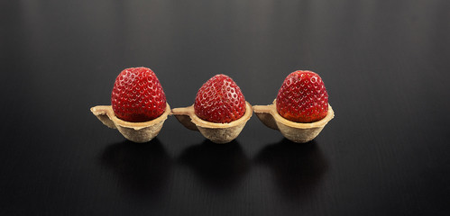 Strawberries in tartlets in the form of a Cup on a black wooden background