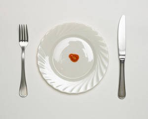SINGLE BAKED BEAN ON WHITE PLATE WITH KNIFE AND FORK