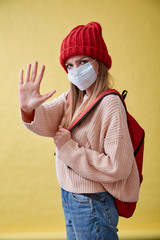 Yong girl in red hat and the medical mask on the yellow background