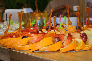 Fruit slicing of orange and apple with colorful plastic skewers on cocktail or a buffet table