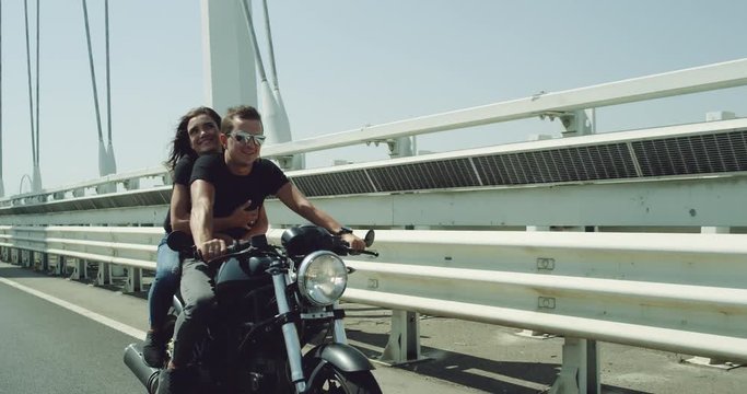 Capturing video in front of the camera young beautiful couple have a ride on the motorcycle in the sunny summer day , on the motorway they enjoy the time together