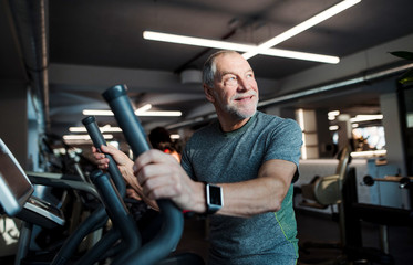 Fototapeta na wymiar A senior man doing strength workout exercise in gym. Copy space.