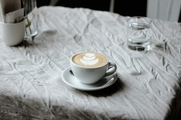 Processed witon a natural linen tablecloth a white cup of coffee with whipped creamh VSCO with m5 preset