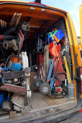 Cargo space of a construction vehicle, loaded with various tools, transport cart, barriers, shovels and brooms