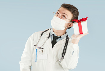 doctor student with a gift in his hands on an isolated blue background.concept medicine and health, holidays and gifts