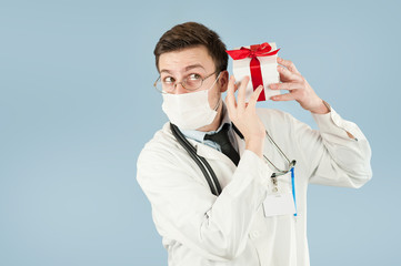 doctor student with a gift in his hands on an isolated blue background.concept medicine and health, holidays and gifts