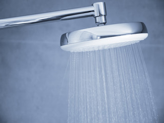 Flowing water from shower head at bathroom interior