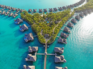 Aerial view of overwater bungalow villas with thatched roofs in the Bora Bora lagoon in French...