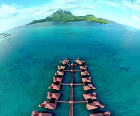 Aerial view of overwater bungalow villas with thatched roofs in the Bora Bora lagoon in French Polynesia - obrazy, fototapety, plakaty