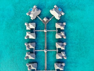 Aerial view of overwater bungalow villas with thatched roofs in the Bora Bora lagoon in French Polynesia - obrazy, fototapety, plakaty