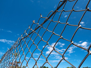 Fence made of metal net on blue sky background
