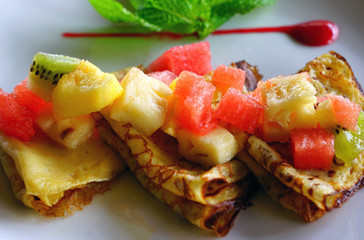 Crepes folded in quarters with fresh fruit, berry coulis and fresh mint