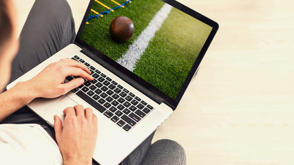 man use mobile Computer , blur image of football match on screen.