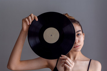Beautiful girl portrait, holding an LP microgroove vinyl record on bright background