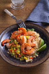 Shrimps with mango avocado and red pepper salsa on cauliflower rice in bowl on wooden table