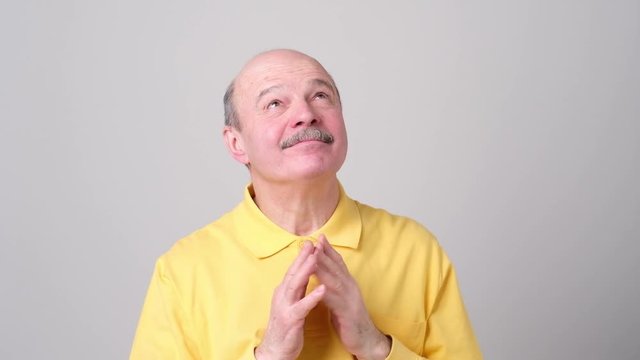 Cunning tricky mature man thinking looking aside and up with hand together