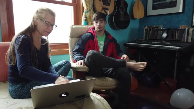 Mature woman, mother, and son, look at a computer screen in a relaxed atmosphere living room while woman rants about what she sees on the screen.
