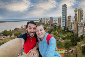happy tourist couple take selfie photo with panoramic view cityscape of the city of Rosario, Argentina. It is the largest city in the province of Santa Fe, in central Argentina. 