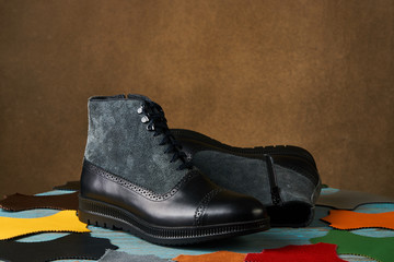 Shoe making concept with mens boots over brown background