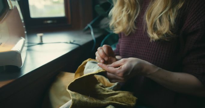 Young woman mending curtain by sewing machine