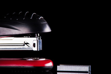red stapler with staples on a black background