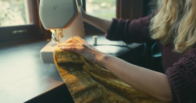 Young woman mending curtains with sewing machine