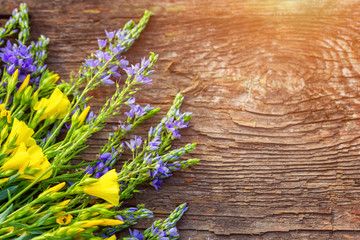 yellow and lilac flowers lie on wooden background, copy space, beautiful postcard background