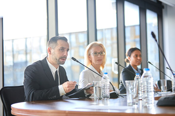 Confident speaker with document reading his report in microphone and explaining its points to...