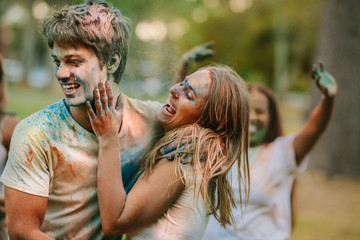 Couple having fun playing holi in a park with friends