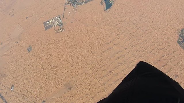 Skydiver parachuting over the desert dunes