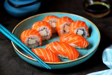 Philadelphia homemade sushi rolls in a blue plate on a black background.