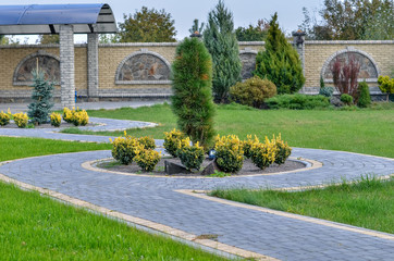 Fragment of paved stone walkway in the garden with green lawn.