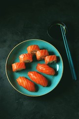 Philadelphia homemade sushi rolls in a blue plate on a black background.