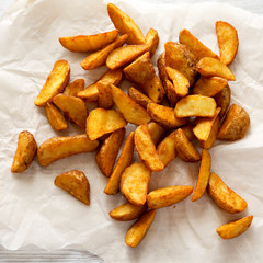 Fried potato wedges on baking sheet. From above, overhead, top view. Close-up.