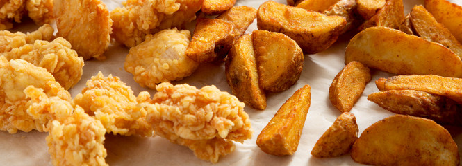 Fried potato wedges and chicken bites. Close-up.