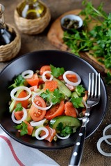 Healthy salad of cherry tomatoes, cucumber, celery, onions, capers and parsley with salted salmon.