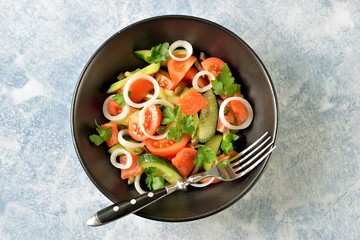 Healthy salad of cherry tomatoes, cucumber, celery, onions, capers and parsley with salted salmon.