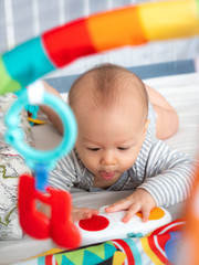 Close up Cute 6 months old mixed race Asian Caucasian boy looking happy smiling and laughing at the camera, healthy child baby boy. Baby starting to crawl, play with toys map gym for brain development