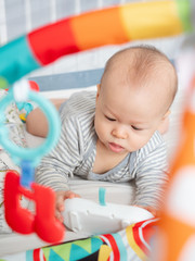 Close up Cute 6 months old mixed race Asian Caucasian boy looking happy smiling and laughing at the camera, healthy child baby boy. Baby starting to crawl, play with toys map gym for brain development