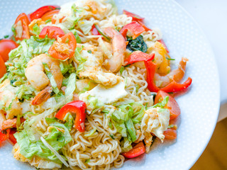 Thai style food spicy instant noodles salad with seafood, shrimps, tomato and vegetables.