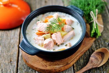 Finnish wild salmon soup with cream on an old wooden background. Rustic style.