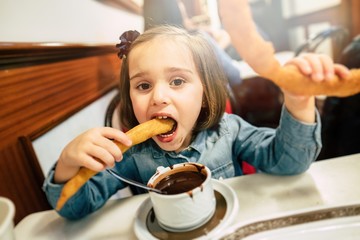 Kid eating churros and chocolate