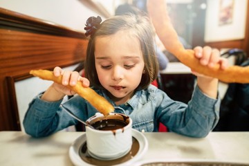 Kid eating churros and chocolate