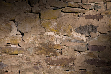 Cracked dilapidated masonry wall lit diagonally