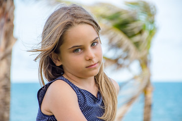 Criança modelo sentada em frente ao mar azul