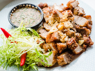 Thai-Laos style deep fried crispy pork with spicy sauce and steamed sticky rice, vegetables, chili