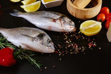 Fish seafood dorado, raw food on black background,  lemon.